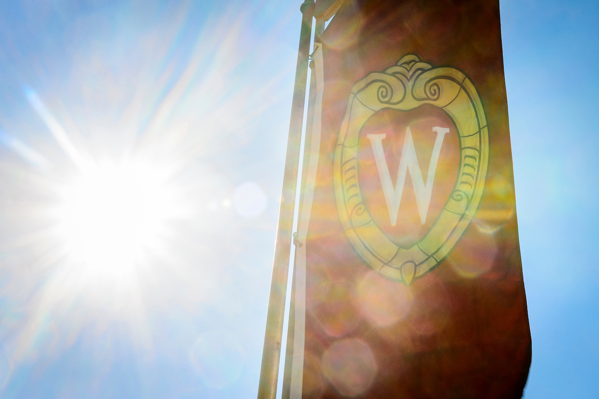 Sunlight shines through an iconic W crest banner on Bascom Hill at the University of Wisconsin-Madison.