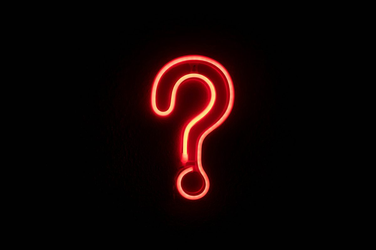 Red neon question mark sign on a black background.